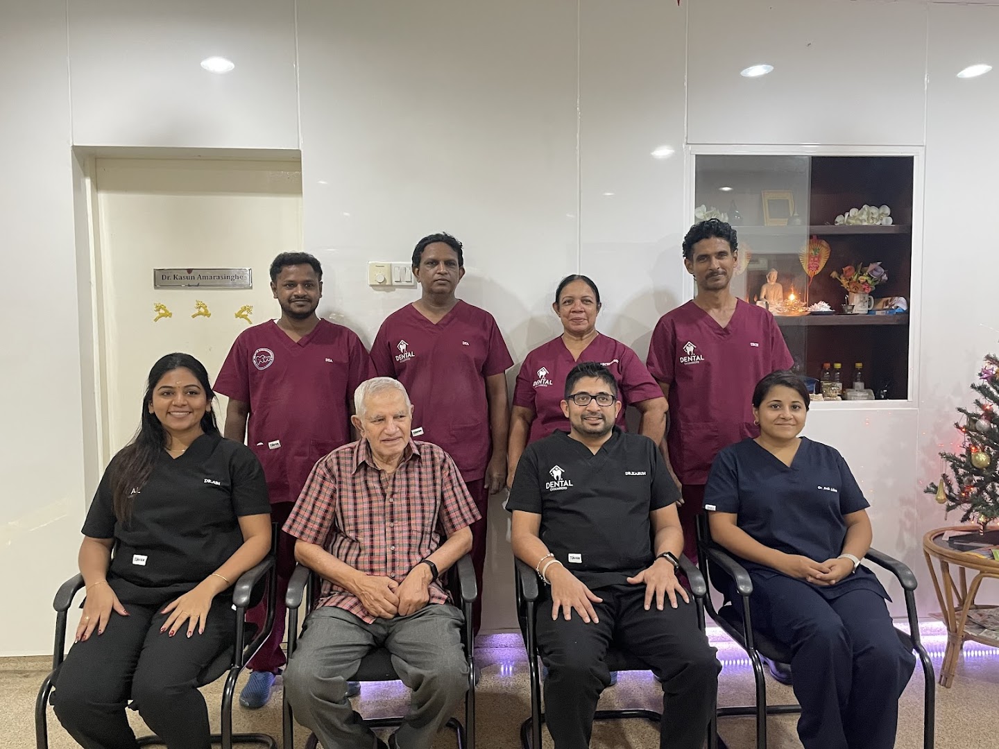 Dental Chambers team in burgundy scrubs with patients and senior staff in the clinic waiting area
